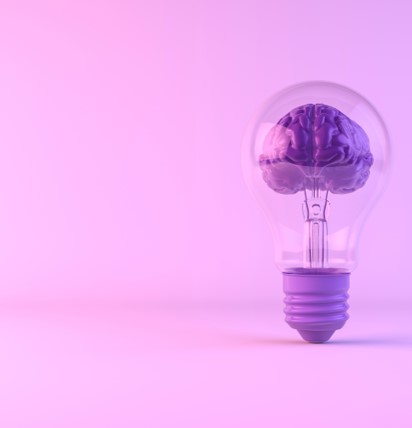 En glödlampa med en hjärna inuti. Allt i lila färgtoner.
