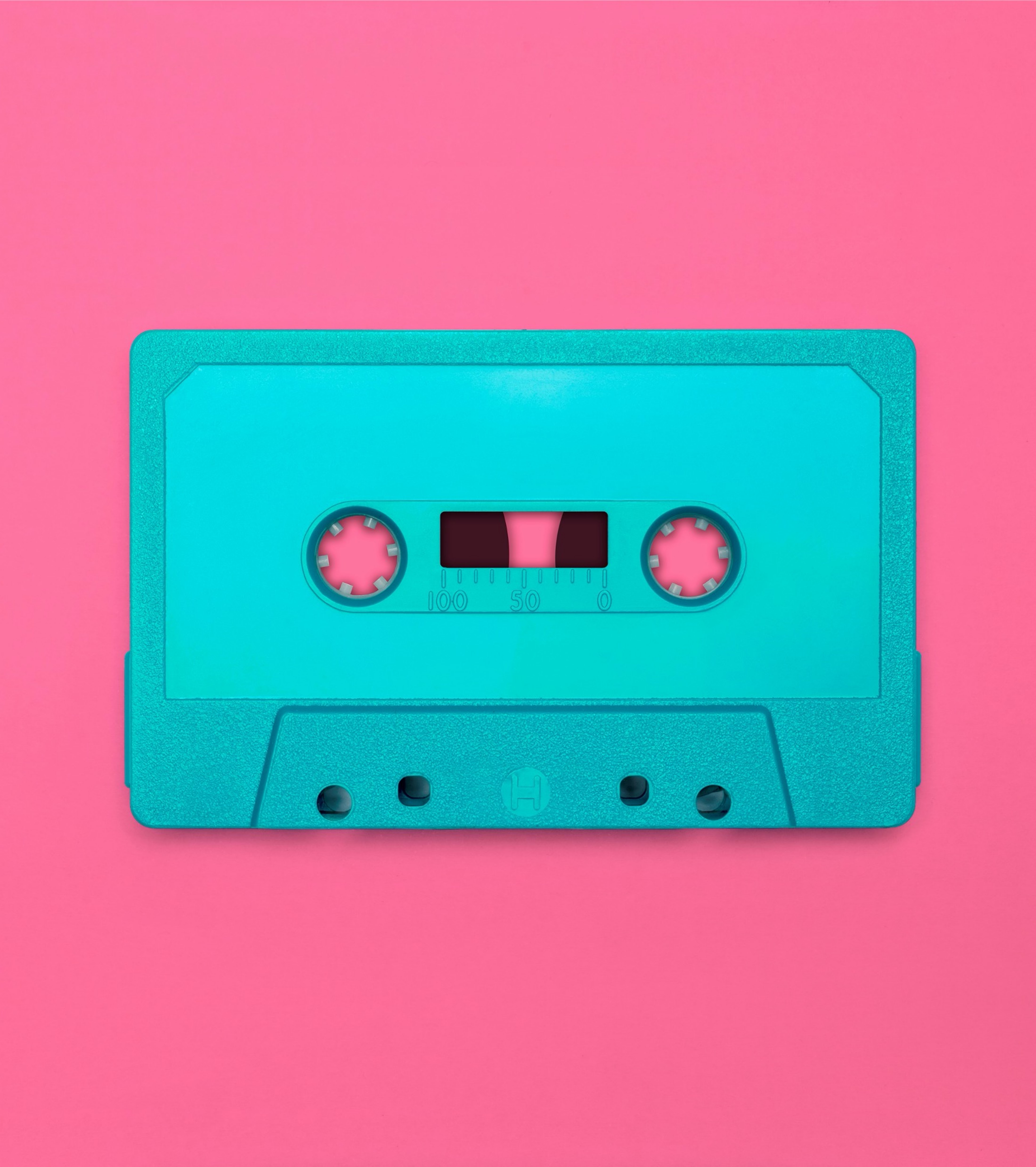 Ett turkost kassettband på rosa bakgrund.